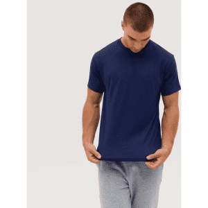 A navy blue T-shirt is held by a person, wearing grey shorts, showcasing its simple design. The image includes a logo.