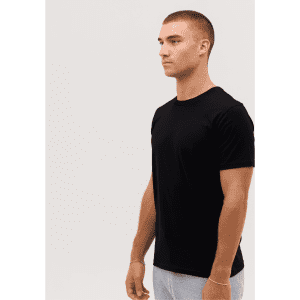 A black Classic Tee worn by a model standing sideways, with a simple, minimalistic design.