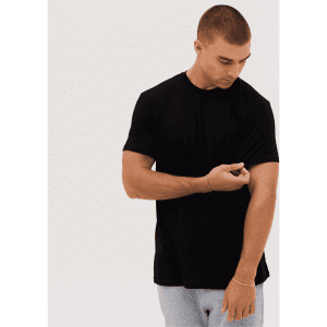 A black T-shirt on a male model adjusting the sleeve, with a plain background.