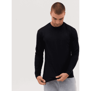 A long sleeve tee in black, worn by a model inspecting the hem, with a casual fit and long sleeves.