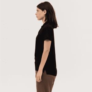 A women's black polo shirt displayed from the side, featuring a fitted design and a collar. It has a logo on it.