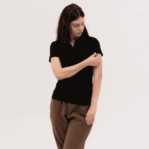 A black women's polo shirt is featured, styled with a relaxed fit and short sleeves. It has a logo on the side.