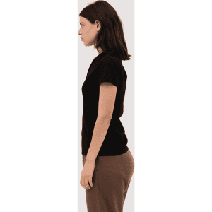 A black women's polo shirt displayed on a model, featuring a simple design and short sleeves.