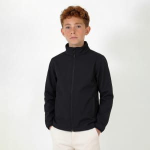 A youth's softshell jacket in black, featuring a zip-up front and a high collar. The model is standing and looking at the camera.