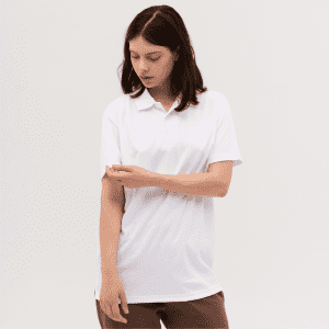 A woman wearing a white polo shirt, looking at her sleeve, set against a plain background. The shirt features a logo.