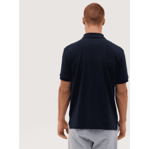 A navy polo shirt with a collar, viewed from the back. The model has short hair and is wearing grey shorts.
