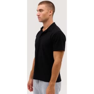 A black polo shirt displayed on a model, featuring a simple design and a classic collar.