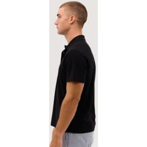 A black polo shirt displayed on a model in profile. The shirt features a collar and short sleeves.