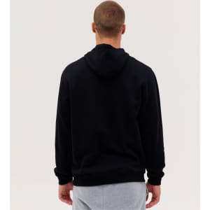 A black hoodie with a kangaroo pocket seen from the back, worn by a person in grey sweatpants.