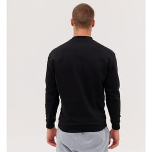 A man is wearing a black sweatshirt, facing away, with light grey trousers. The sweatshirt features a logo.