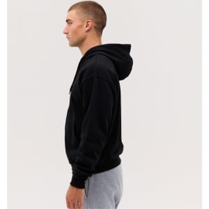 A black zip hoodie is displayed on a model, showcasing a side view against a plain background.