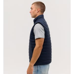A navy blue puffer vest displayed on a model from the side, featuring a high collar and a sleek design.