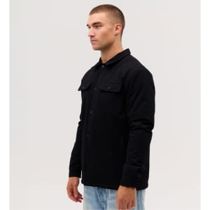 A black Studio Canvas Jacket is displayed on a model, showcasing its button-up design and front pockets.