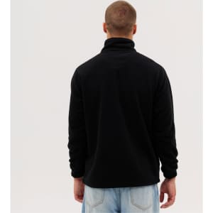 A black polar fleece 1/4 zip garment viewed from the back, worn by a person with short hair and a casual outfit.