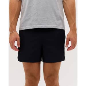 A pair of black running shorts, displayed on a person wearing a grey t-shirt, with a logo on the shorts.