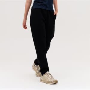 Black track pants with side pockets, worn by a person in gold sneakers against a plain background.