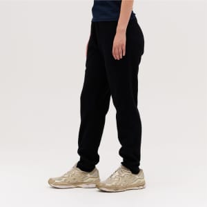 Black track pants featured alongside a person wearing gold sneakers, with a simple, neutral background.
