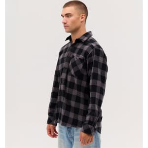 A long sleeve flannel shirt in black and grey check pattern, featuring a pocket and a logo.