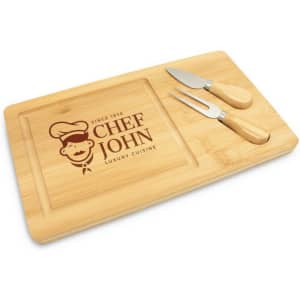 A bamboo cheese board with two metal knives, featuring a logo and a carved area for serving.