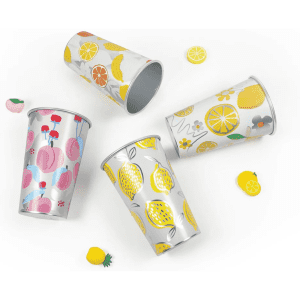 A set of four colourful, patterned cups featuring fruits like lemons, cherries, and peaches, with a shiny silver interior.