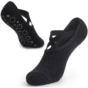 A pair of black yoga socks featuring a cross-strap design and silicone grip dots on the sole.