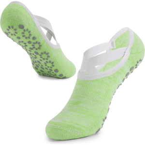 Green yoga socks with a non-slip grip and crossed white straps, showcasing a textured sole for stability.