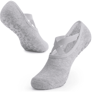 A pair of grey yoga socks with crisscross straps and textured soles for added grip. Features a logo.