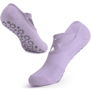 A pair of lavender yoga socks featuring cross straps and non-slip grips on the soles.