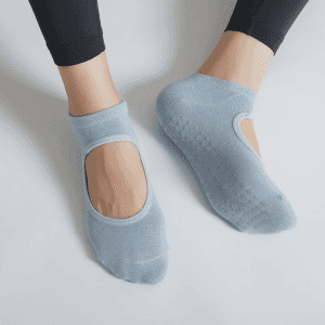 A pair of light blue yoga socks with an open top, featuring grip soles, worn on a person's feet.