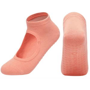 A pair of peach yoga socks with an open top design and textured grip on the soles.