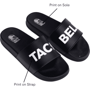 A pair of black PVC slides featuring a prominent logo and text printed on the strap and sole.