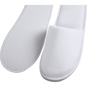 A pair of white hotel slippers with textured and smooth surfaces, featuring a simple design and soft materials.