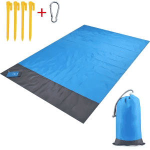 A blue and grey polyester picnic blanket laid out, accompanied by yellow pegs and a grey pouch with a carabiner.