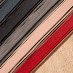 A selection of Bondi A5 Leather Notebooks in various colours, including black, grey, pink, and red, stacked together.