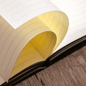 An A5 leather notebook featuring lined pages, with a yellow section visible, set on a wooden surface.