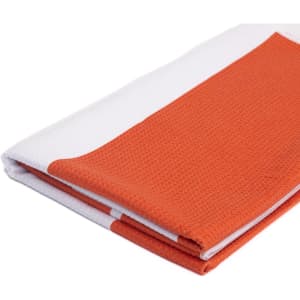 An orange and white sandless beach towel, neatly folded, featuring a textured surface and a logo.