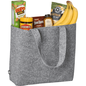 A grey felt shopper bag containing bananas, Tim Tams, Vegemite, Shapes, and sea salt. The bag has sturdy handles and a logo.