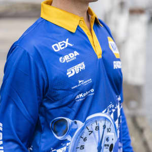 A blue and yellow long sleeve fishing polo featuring a logo and a dynamic sublimated design.