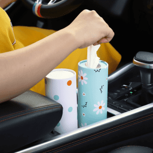 A light blue and white car cup tissue holder with a floral design, placed in a vehicle's cup holder, with tissues being pulled out.