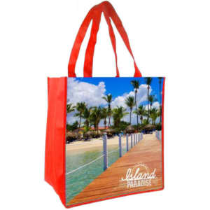 A red tote bag featuring a full-colour image of a tropical beach scene with palm trees and a wooden walkway.
