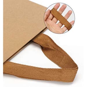 A brown recycled paper bag with a textured paper webbed handle, displayed with a hand holding the handle.