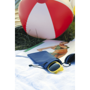 A navy pouch with sunglasses, placed on a white towel beside a beach ball and a magazine. The pouch has a drawstring closure.