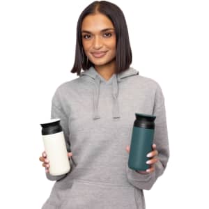 A drink bottle in white and teal, featuring a logo, held by a person in a grey hoodie.