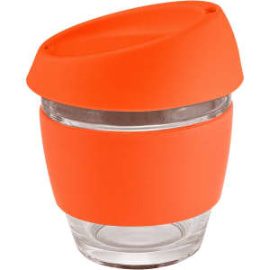 A glass coffee cup with a clear body and an orange silicone lid and band. It has a modern design and a logo.