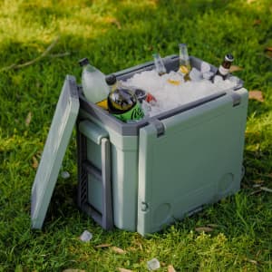 A green cooler box filled with ice and various drinks, featuring a lid partially opened.