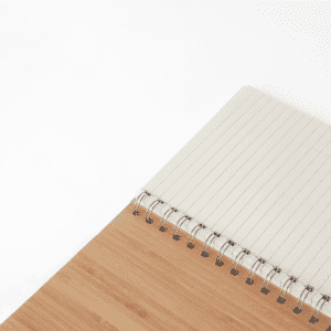 A bamboo notebook with a spiral binding, featuring a textured bamboo cover and lined pages inside.