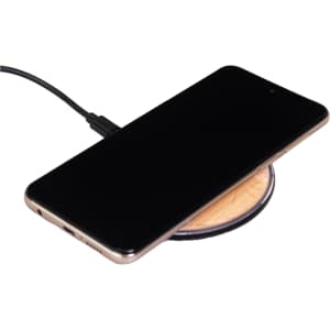 A bamboo wireless charger featuring a circular design with a smartphone placed on top, connected by a charging cable.