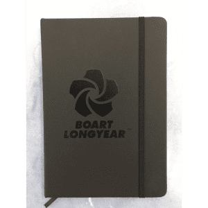 A dark grey notebook with a logo on the cover and an elastic band closure.