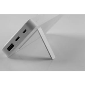 A white power bank featuring multiple ports, positioned on a stand for display.