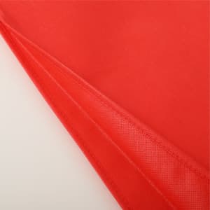 A red non-woven tote bag with a smooth texture and a stitched seam, featuring an interior lining.